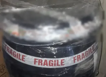 A sealed shipping barrel, wrapped and taped, loaded in a container for Nigeria